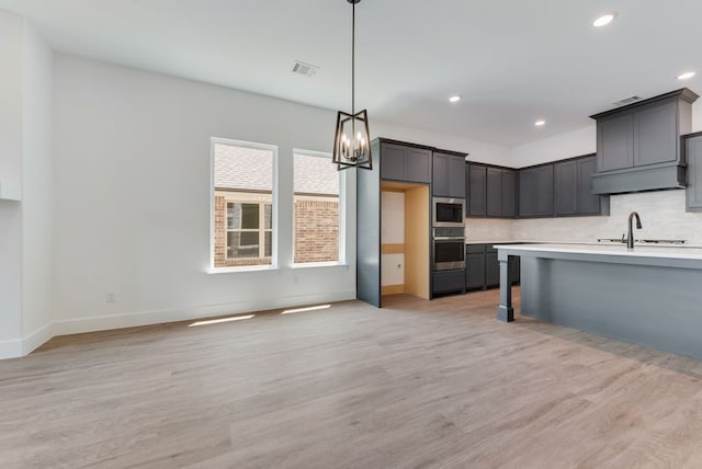 kitchen featuring tasteful backsplash, visible vents, light countertops, appliances with stainless steel finishes, and a sink