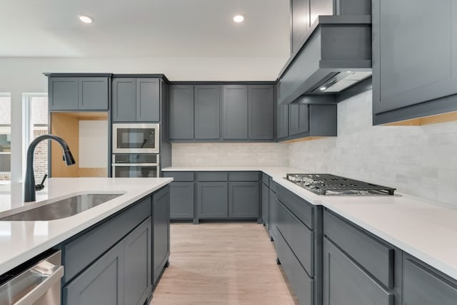 kitchen with a sink, stainless steel appliances, custom exhaust hood, and light countertops