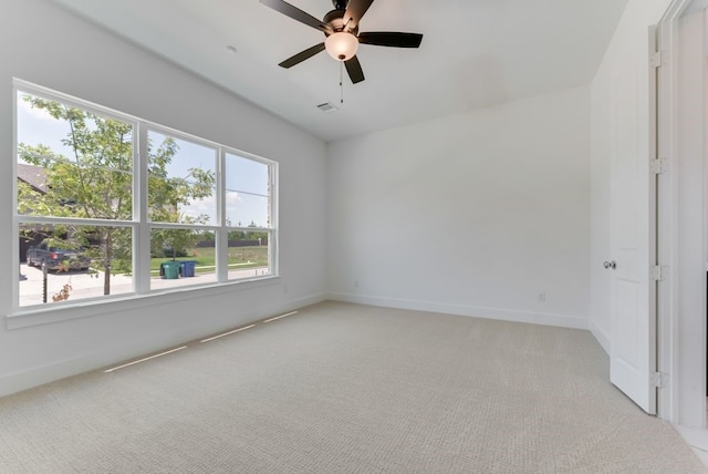 empty room with light carpet, visible vents, baseboards, and a ceiling fan