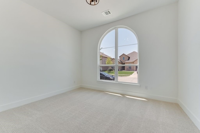 carpeted spare room featuring visible vents and baseboards