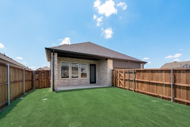 back of property featuring brick siding, a fenced backyard, a lawn, and a patio area