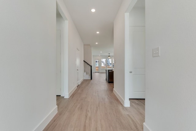 hall featuring light wood finished floors, recessed lighting, stairs, and baseboards