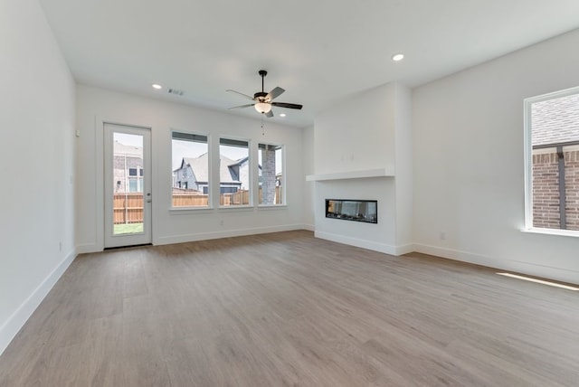 unfurnished living room with a wealth of natural light, wood finished floors, and ceiling fan