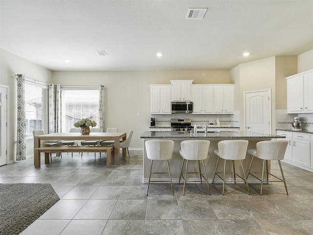 kitchen with visible vents, tasteful backsplash, appliances with stainless steel finishes, and a breakfast bar area