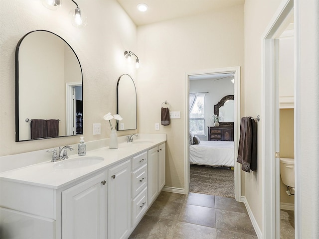 full bath with a sink, baseboards, ensuite bath, and double vanity