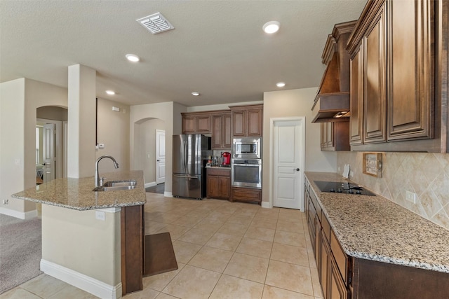 kitchen featuring visible vents, a sink, open shelves, arched walkways, and appliances with stainless steel finishes