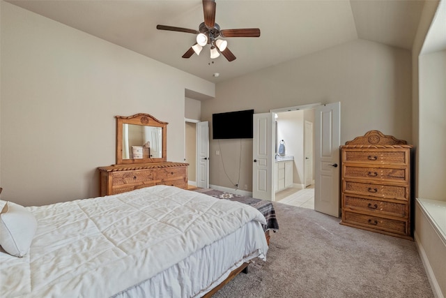 bedroom featuring baseboards, lofted ceiling, light carpet, ensuite bathroom, and a ceiling fan