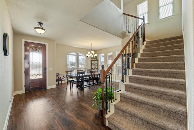 entryway featuring a chandelier, stairs, dark wood-type flooring, and baseboards