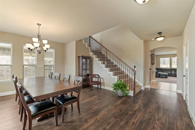 dining room with baseboards, stairway, an inviting chandelier, wood finished floors, and arched walkways