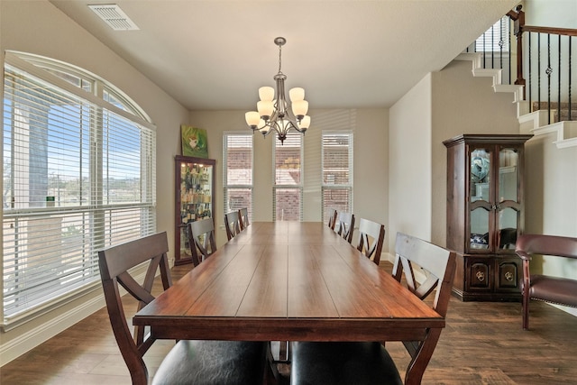 dining space with a notable chandelier, stairs, visible vents, and wood finished floors