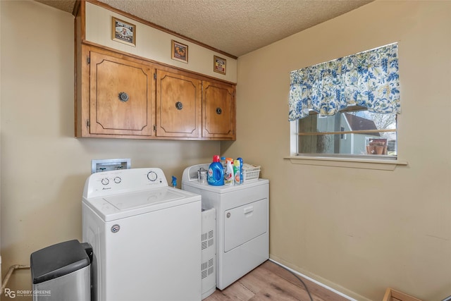 washroom with cabinet space, separate washer and dryer, light wood-style floors, and a textured ceiling