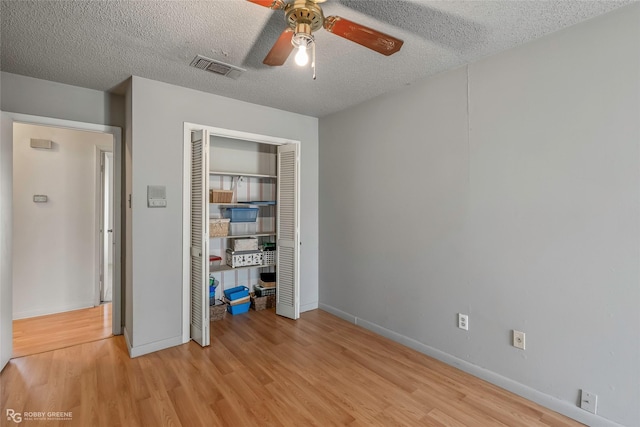 unfurnished bedroom with light wood-type flooring, a textured ceiling, a closet, and visible vents