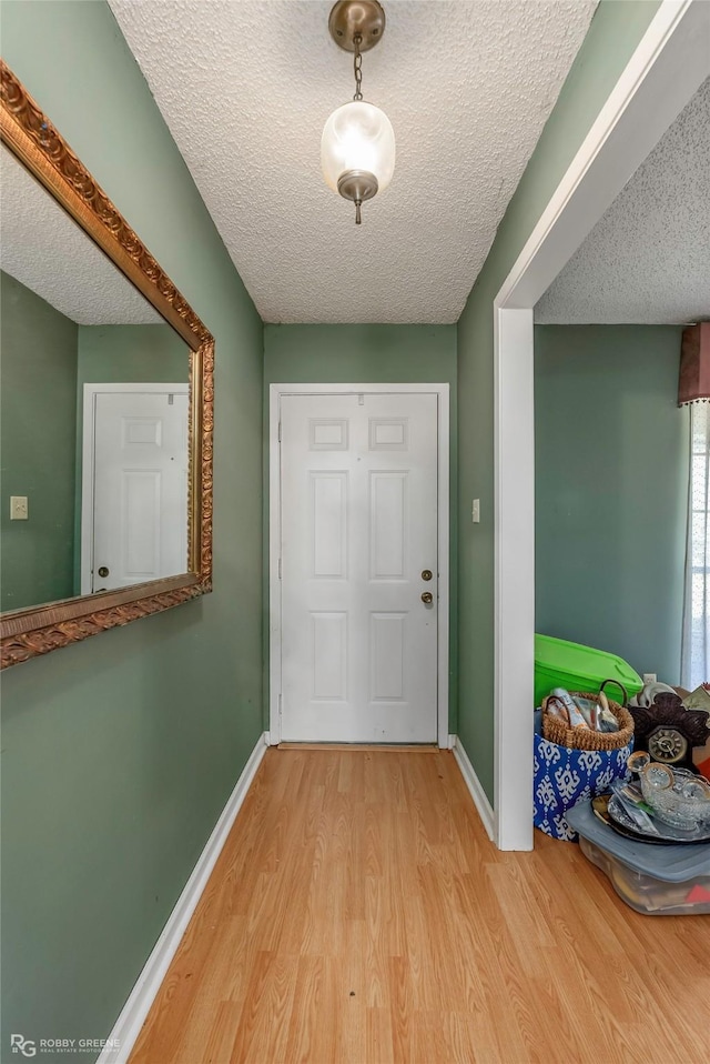 doorway featuring wood finished floors, baseboards, and a textured ceiling