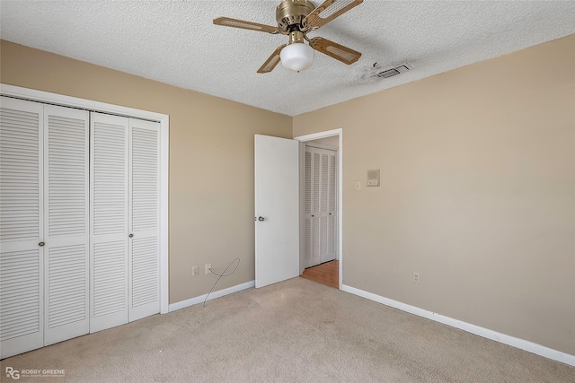 unfurnished bedroom with baseboards, visible vents, a closet, a textured ceiling, and carpet flooring