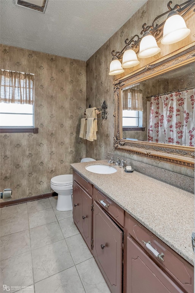 full bathroom with a wealth of natural light, toilet, a textured ceiling, and vanity