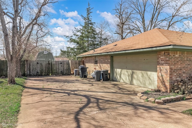 view of home's exterior with a detached garage, a gate, fence, and brick siding