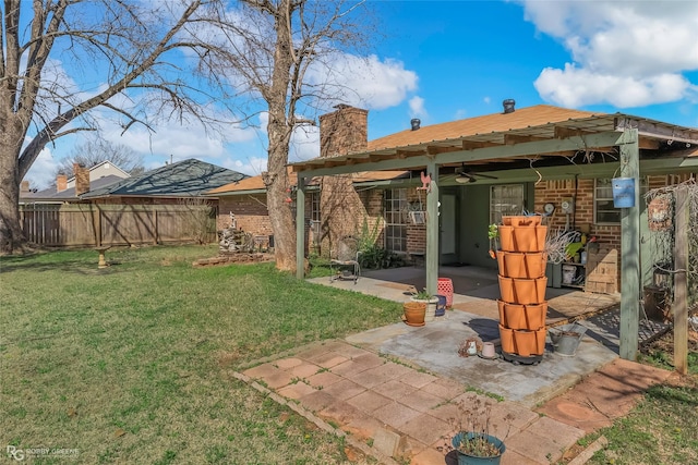 back of house with brick siding, fence, a chimney, a yard, and a patio area