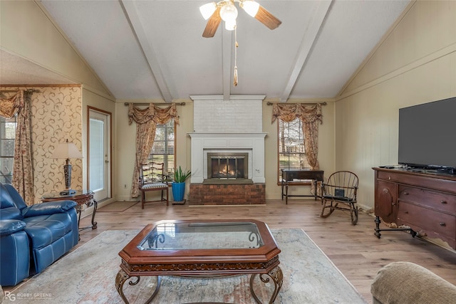 living area featuring a fireplace, wood finished floors, vaulted ceiling with beams, and a ceiling fan