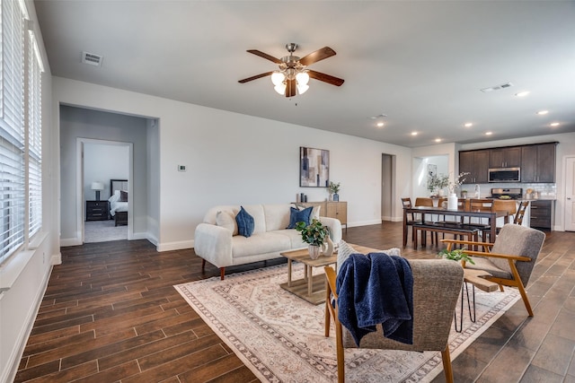 living area featuring baseboards, visible vents, a ceiling fan, and wood finish floors