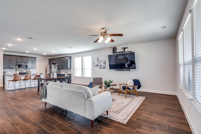 living room featuring visible vents, baseboards, recessed lighting, ceiling fan, and dark wood-type flooring