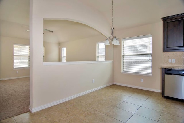 unfurnished dining area featuring light tile patterned floors, baseboards, light colored carpet, and a ceiling fan