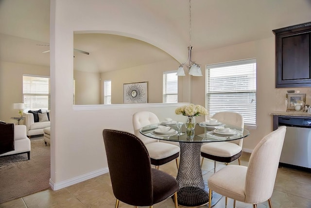 dining area featuring light tile patterned floors, baseboards, and arched walkways