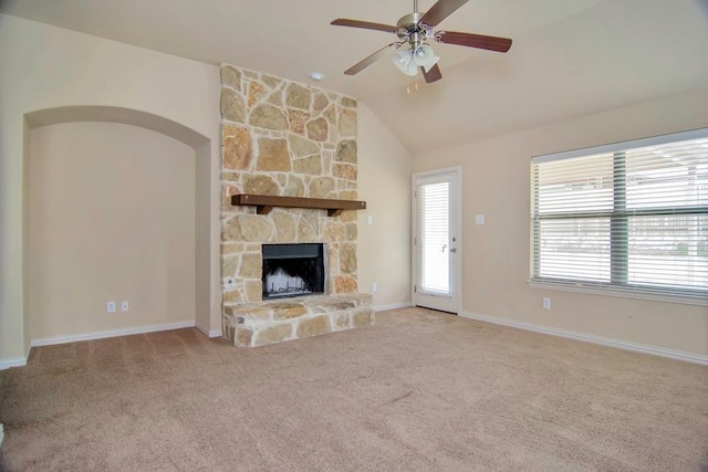 unfurnished living room with baseboards, carpet, lofted ceiling, a stone fireplace, and a ceiling fan