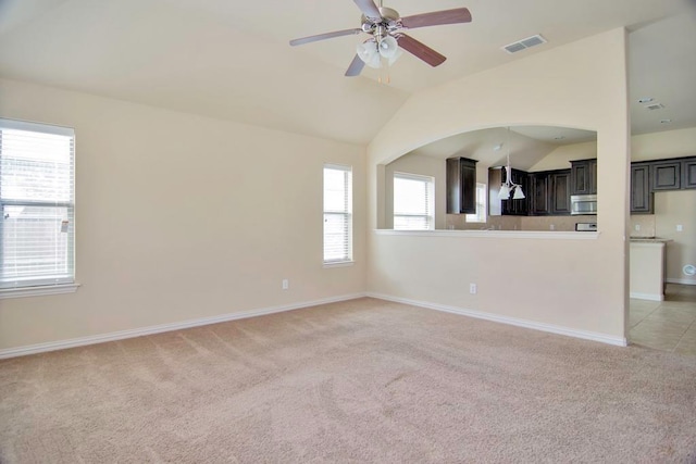 unfurnished living room with visible vents, baseboards, vaulted ceiling, light carpet, and a ceiling fan