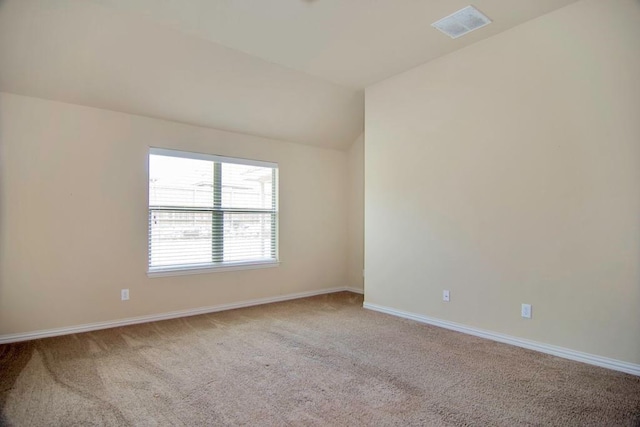 spare room with vaulted ceiling, carpet, visible vents, and baseboards