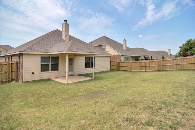 back of house with a yard, a patio, a fenced backyard, and a shingled roof