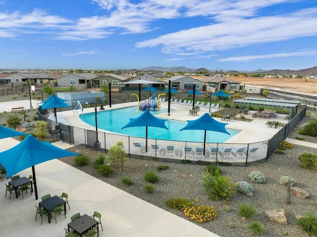 pool with a patio, a mountain view, fence, and a residential view