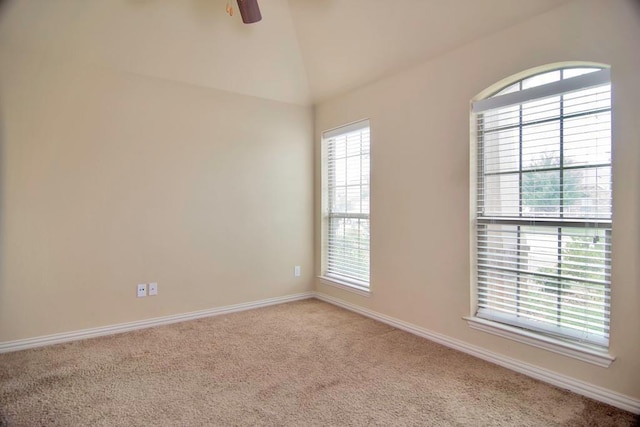 carpeted spare room featuring lofted ceiling, baseboards, and ceiling fan