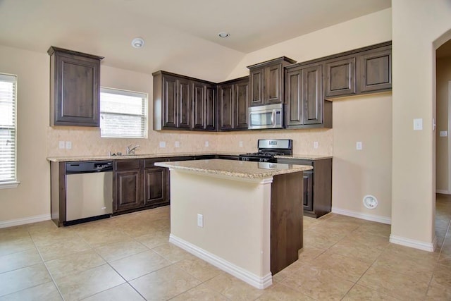 kitchen with tasteful backsplash, dark brown cabinets, appliances with stainless steel finishes, and lofted ceiling