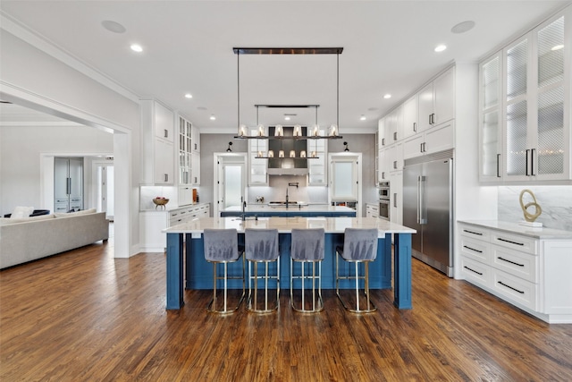 kitchen with white cabinetry, stainless steel appliances, dark wood-type flooring, and ornamental molding