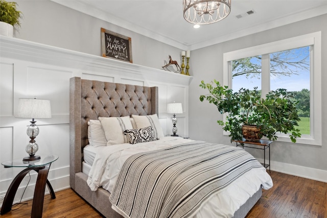 bedroom featuring a notable chandelier, visible vents, baseboards, and wood finished floors