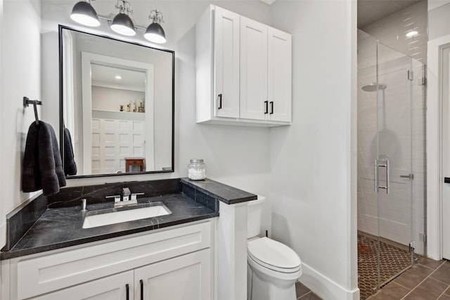 bathroom featuring toilet, a stall shower, vanity, and tile patterned flooring