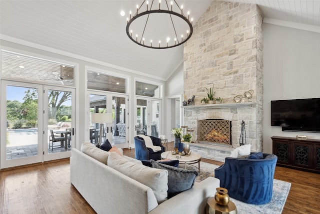 living room with ornamental molding, a stone fireplace, ceiling fan with notable chandelier, wood finished floors, and high vaulted ceiling