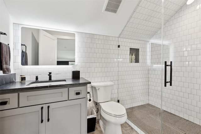 bathroom featuring vanity, visible vents, a shower stall, tile walls, and toilet