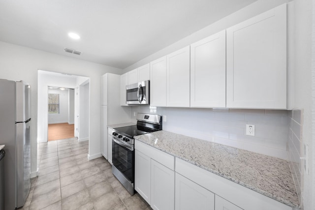 kitchen featuring visible vents, appliances with stainless steel finishes, white cabinets, and decorative backsplash