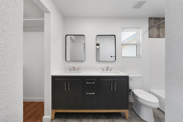 full bath featuring double vanity, toilet, visible vents, and a sink