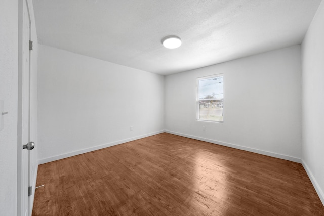 unfurnished room featuring wood finished floors, baseboards, and a textured ceiling