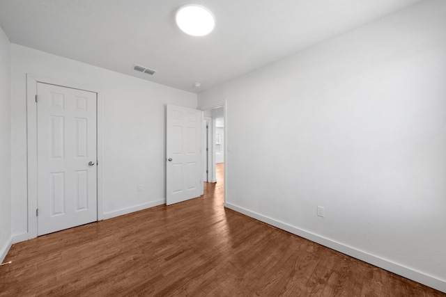 unfurnished bedroom with visible vents, baseboards, and wood finished floors