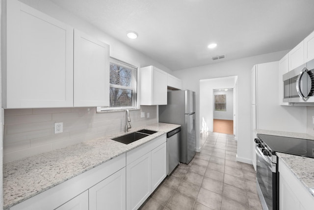 kitchen featuring visible vents, a sink, stainless steel appliances, white cabinetry, and backsplash