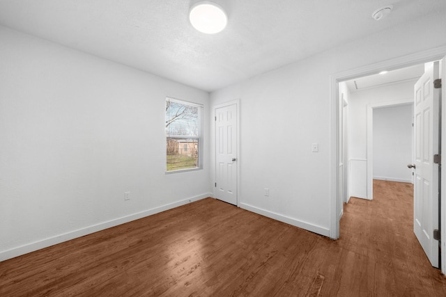 unfurnished bedroom with attic access, wood finished floors, baseboards, and a closet