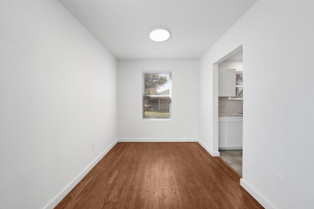 spare room with baseboards and wood finished floors