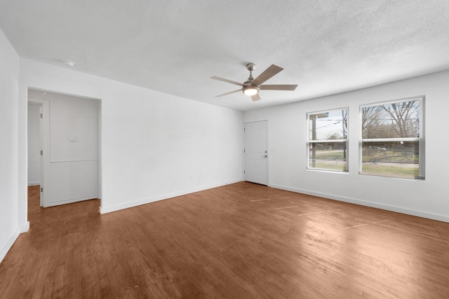 spare room with baseboards, a textured ceiling, wood finished floors, and a ceiling fan