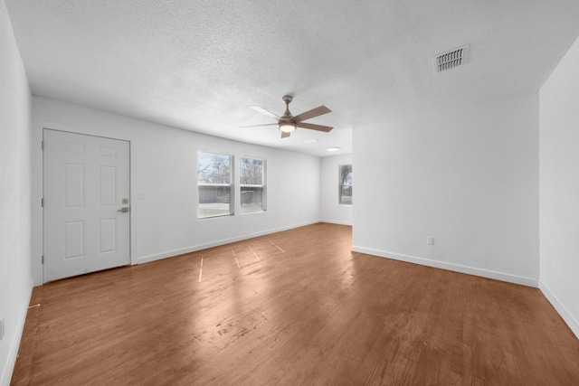 interior space with visible vents, a ceiling fan, a textured ceiling, wood finished floors, and baseboards