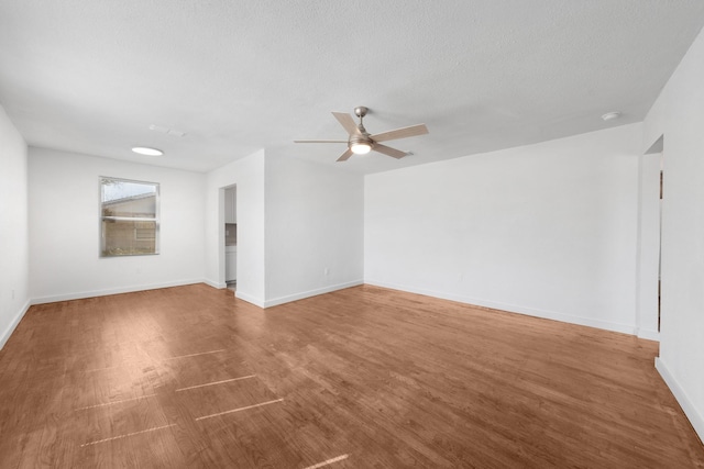 spare room with a textured ceiling, baseboards, ceiling fan, and wood finished floors