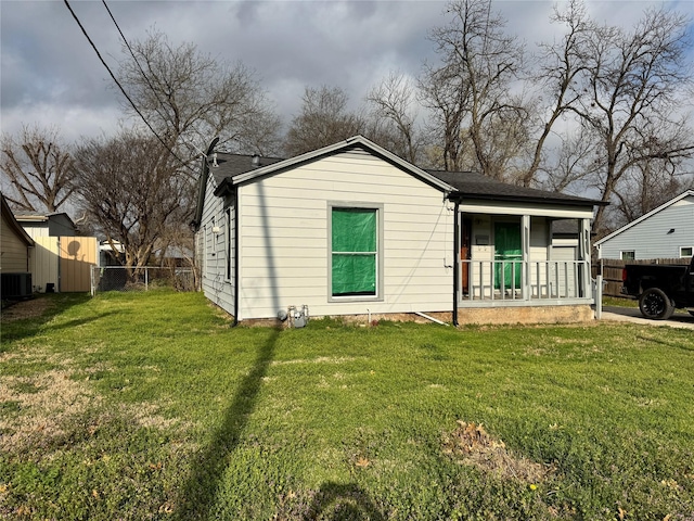 view of front of home with a porch, cooling unit, fence, and a front yard