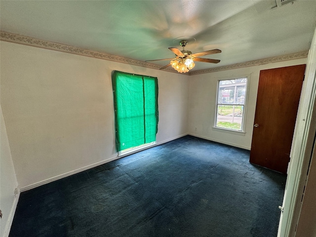 spare room with baseboards, ceiling fan, and dark carpet